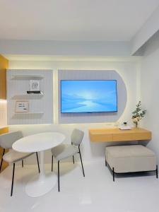 a room with a table and chairs and a tv on the wall at Simple White Scape at Mesavirre Bacolod in Bacolod