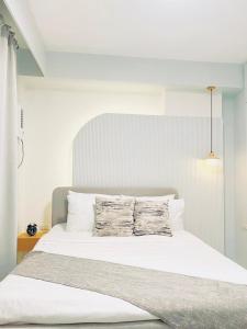 a white bed with two pillows on top of it at Simple White Scape at Mesavirre Bacolod in Bacolod