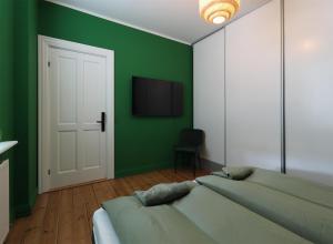a green bedroom with two beds and a television at Danmarksgade XXL-Suites in Aalborg