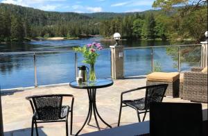 a patio with a table and chairs and a view of a lake at Hamsun Panorama med sauna in Åmli