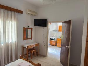a room with a bedroom with a desk and a television at Helena & Giorgio Rooms Cfu in Agios Georgios