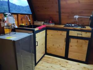 a kitchen with wooden cabinets and a sink and a stove at Cabaña El Resguardo in La Capilla