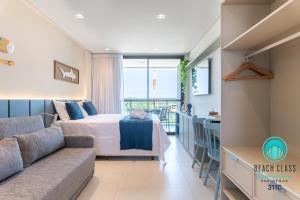 Refúgio Verão - Flat de alto padrão na praia do Cupe - Porto de Galinhas في بورتو دي غالينهاس: غرفة نوم بها سرير وأريكة