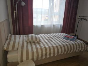 a bed with a striped comforter in front of a window at Perłowy in Biłgoraj +2 photos