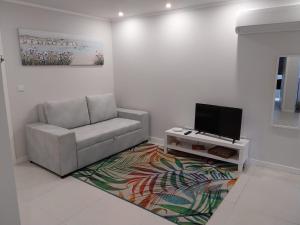 a living room with a couch and a television at Apartamentos do Lameirinho in Angra do Heroísmo