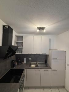 a kitchen with white cabinets and a sink at Moselzeit - Moderne Ferienwohnung mit Terrasse und Burgblick in Bernkastel-Kues