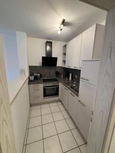 a kitchen with white cabinets and a stove top oven at Moselzeit - Moderne Ferienwohnung mit Terrasse und Burgblick in Bernkastel-Kues