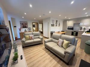 a living room with two couches and a kitchen at Woodway Lodge in Dumfries