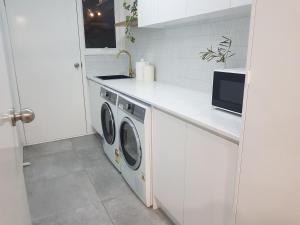 een witte keuken met een wasmachine en droger bij Entire home in Cranbourne West in Cranbourne