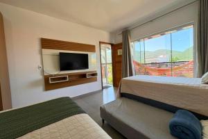 Un dormitorio con dos camas y un televisor de pantalla plana. en Dunas Studios, en Garopaba