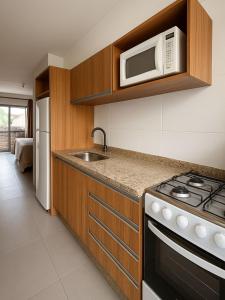 una cocina con estufa y microondas en Dunas Studios, en Garopaba