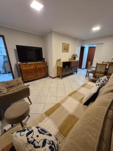 un salon avec un canapé et une télévision à écran plat dans l'établissement Pé na areia, 4 quartos, Garagem Enorme para até 2 carros médio porte, à Balneário Camboriú