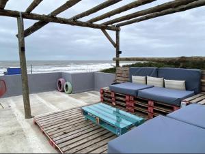 a patio with a couch and a table and the beach at Ostende frente al mar in Ostende
