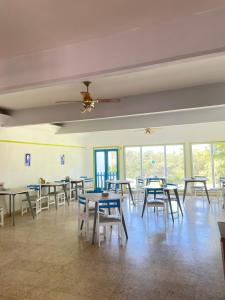 Hotel Bella Vista في فيلا جيزيل: غرفة فارغة فيها طاولات وكراسي ونوافذ