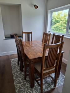 a wooden dining room table with chairs and a window at Charming tree top cottage overlooking River Teifi in Cilgerran