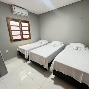 two beds in a room with a window at Casa com 3 dormitórios na Praia do Preá com Piscina in Prea +10 photos