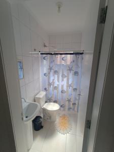 a white bathroom with a toilet and a sink at Aconchego em Bertioga in Bertioga