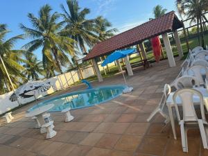 una piscina en un patio con sillas y sombrillas en Casa de Praia com Piscina em frente à praia para até 32 pessoas, en Vera Cruz de Itaparica