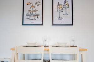 a dining room table with two white chairs and two framed illustrations at New Street C - City Centre in Worcester