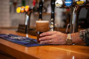 a hand holding a cup of coffee on a table at The Courie Inn in Killin