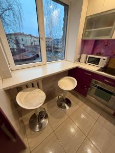 eine Küche mit zwei Hockern und zwei Fenstern in der Unterkunft Armin Castle to Stay in Jelgava