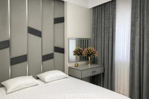 Un dormitorio con una cama blanca y un espejo. en Tashkent Park View Suites - ApartmentHotels uz, en Tashkent