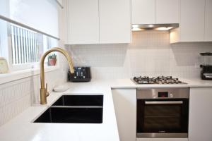 een witte keuken met een spoelbak en een fornuis bij Entire home in Cranbourne West in Cranbourne +8 foto's