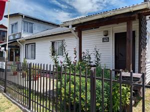 a white house with a fence in front of it at Entre lagos Departamento in Puyehue