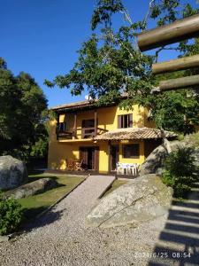 a yellow house with rocks in front of it at Lorena'Haus in Bombinhas