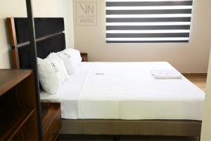 a bed with white sheets and pillows in a room at Hotel Vía Norte in Tuxtla Gutiérrez