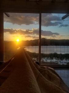 a view of the sunset from a bedroom window at Punta El Tesoro - Playa Privada al Lago in Potrero de los Funes