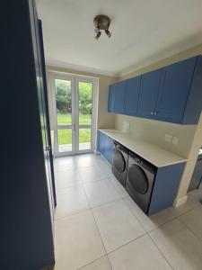 una cucina con armadi blu e lavatrice di Airlie Well a Constantia