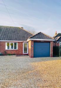 een rood bakstenen huis met een blauwe garage bij Simla Bungalow, Tetney in Tetney