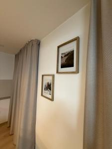 two pictures on a wall next to a curtain at Compleks by Karlus in Jelgava +7 photos