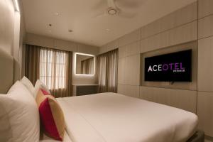 a bedroom with a bed and a tv on a wall at Aceotel Premier Ujjayanta, Ujjain in Ujjain