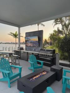 a patio with chairs and a grill and a television at Coastal River Oasis in Cape Coral