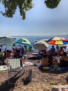 a group of people sitting on a beach with umbrellas at entrre lagos Departamento in Puyehue
