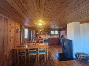 una cucina con tavolo, sedie e soffitto in legno di Fjellvang a Haglebu Altre 5 foto