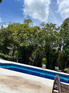 a swimming pool with chairs and trees in the background at Chalé Alpes da Nascente in Salesópolis