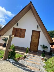 a white house with wooden doors and cacti in front at Chalé Alpes da Nascente in Salesópolis