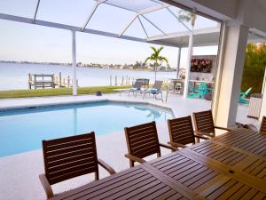 a swimming pool with chairs and a table with a view of the water at Coastal River Oasis in Cape Coral