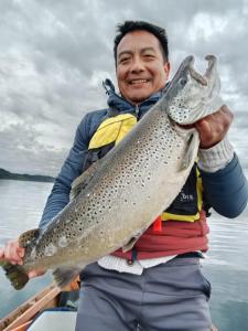 a man holding a fish in a boat at entrre lagos Departamento in Puyehue +1 photo