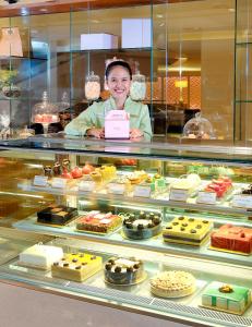 a woman standing in front of a display of desserts at Mandarin Oriental Jakarta in Jakarta