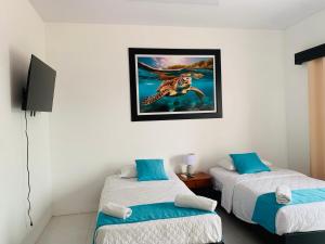 a room with two beds and a picture on the wall at Bluefootedboobies in Puerto Villamil