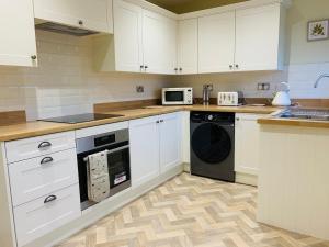 a kitchen with white cabinets and a black dishwasher at Newly renovated countryside retreat in Scorton in Scorton