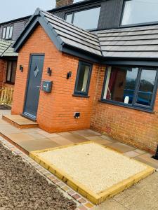 une maison en briques avec une porte noire et une terrasse dans l'établissement Wardenlea, à Scorton