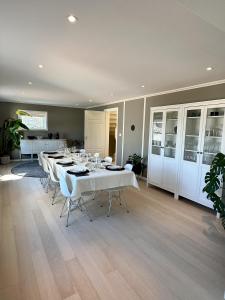 Un comedor con mesas blancas y sillas blancas. en Spacious Group Villa with Jacuzzi and Views, en Askøy