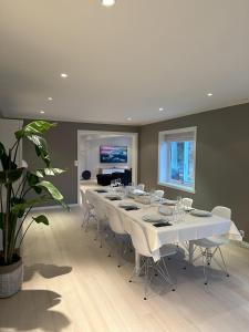 un comedor con una mesa larga y sillas blancas en Spacious Group Villa with Jacuzzi and Views, en Askøy