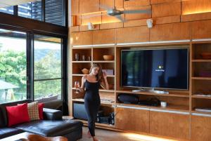 a woman in a black dress standing in front of a tv at The Cassowary - Luxury Rainforest Retreat in Cassowary