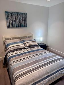 a bed in a bedroom with a painting on the wall at A&A Resident in North Vancouver